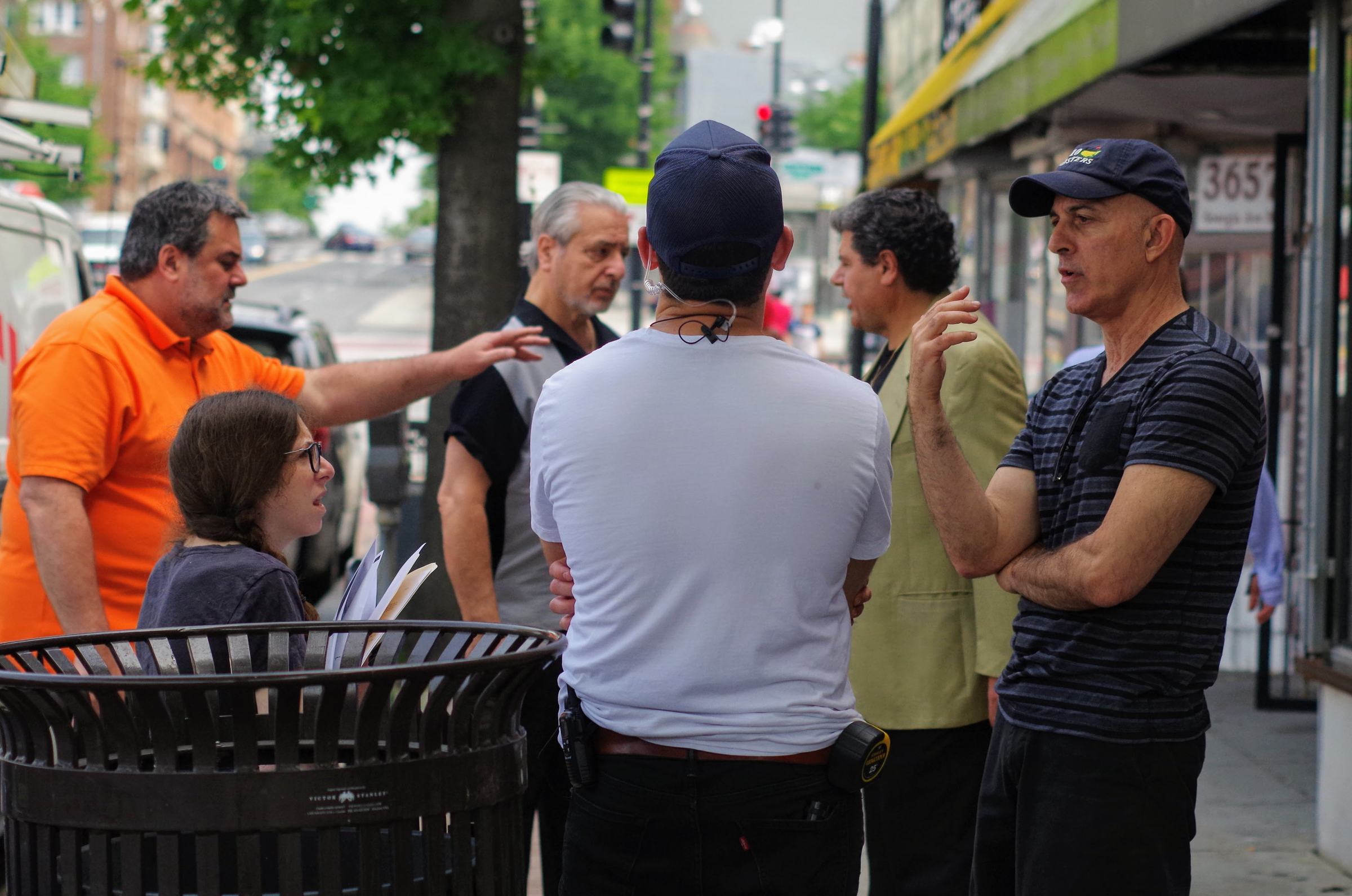 Director talking through a scene with cast and crew on a city sidewalk