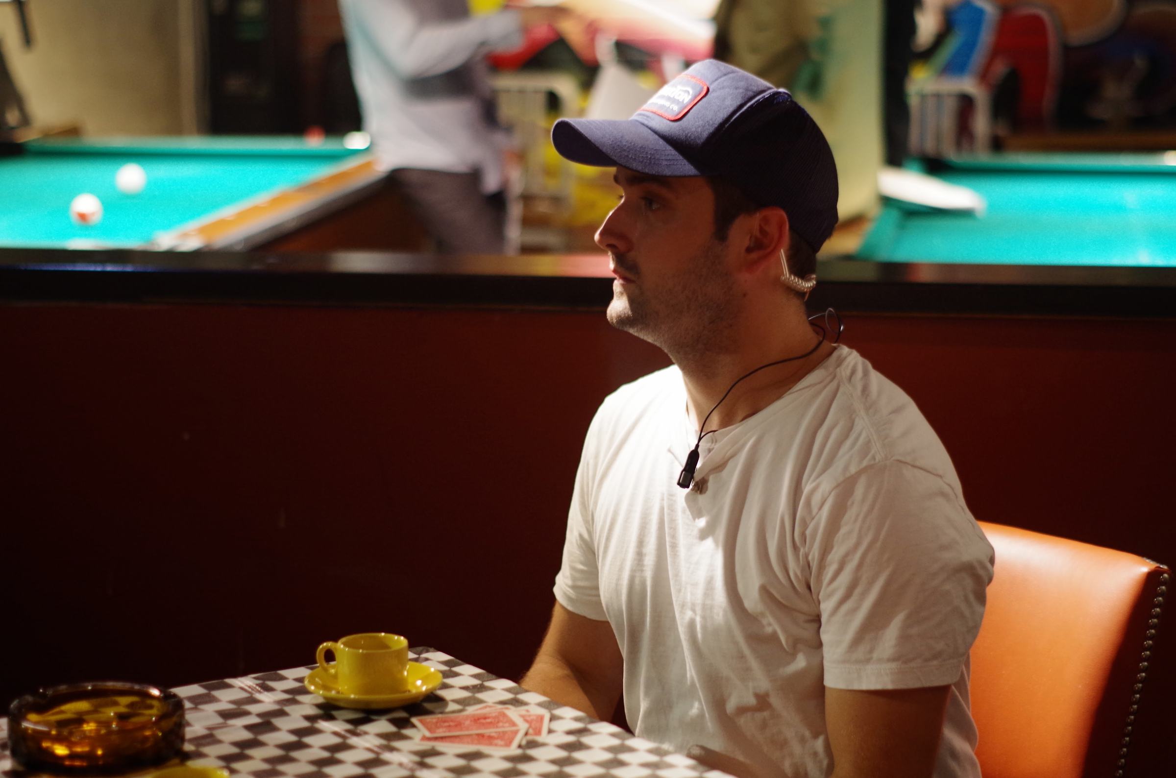 Crew member with an earpiece waiting between takes on a pool hall set